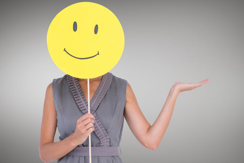 Image: woman covering face with happy face emoji