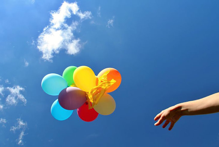 Hand releasing balloons into the sky