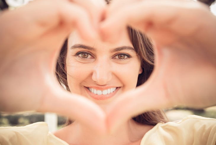Woman smiling and making heart of fingers